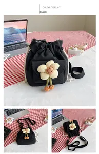 Detail of black canvas drawstring bucket bag with floral decor and cherry charms