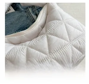 Close-up of white quilted puffer bag showing soft padded texture and spacious interior