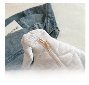 Detail of smooth gold metal zipper and white quilted padded fabric on cloud bag