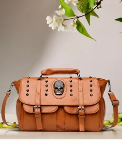 Detail of tan leather handbag featuring a crystal skull accent and metallic rivets