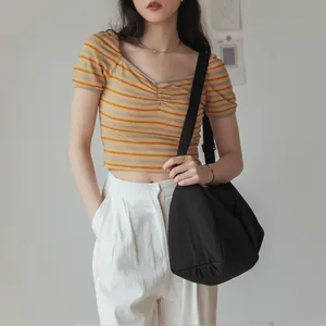 Grand sac à bandoulière en toile noire minimaliste avec un crop top rayé pour un look décontracté