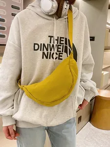 Levendige gele nylon halve maan crossbody tas gestyled op een grijs dames sweatshirt