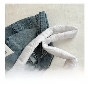 Detail of the white quilted puffer bag featuring a wide padded strap and metal zipper