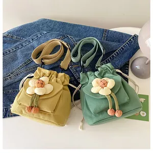 Detail of canvas bucket bags in yellow and green with 3D flower charms and drawstrings