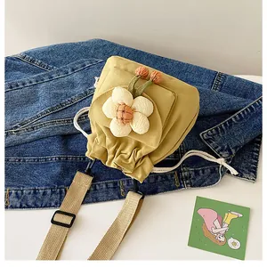 Detail of yellow canvas bucket bag with plush flower and adjustable woven strap