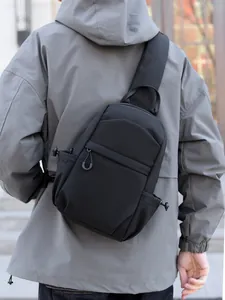 Men's minimalist black multi-functional chest bag with adjustable strap in outdoor setting
