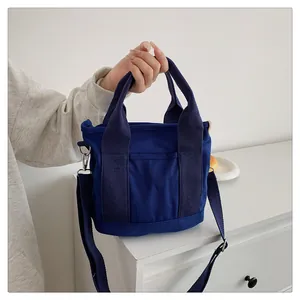Dettagli macro della borsa in tela blu scuro con manici rinforzati e tasca frontale