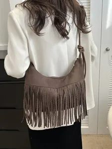 Deep brown crescent suede shoulder bag featuring long fringe and a stylish knotted strap