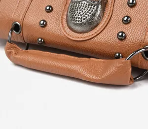 Detail of lychee pattern leather handle and silver metal skull studs on a brown bag