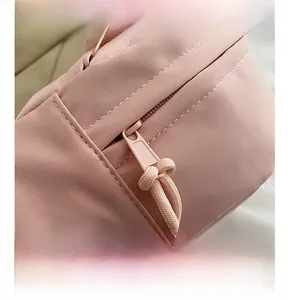 Detail of pink nylon crossbody bag featuring smooth metal zippers and white stitching