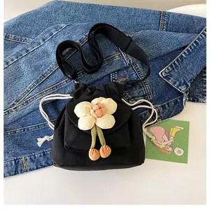 Close-up of black canvas bucket bag with 3D white flower detail and drawstring closure