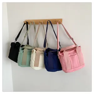 Serie di borse tote in tela nera verde crema blu e rosa su appendino in legno