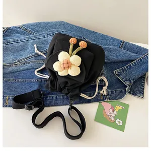 Detail of a black canvas drawstring bucket bag with colorful 3D floral accents