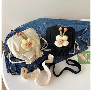 Detail of cream and black canvas drawstring bucket bags with 3D floral accents