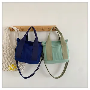 Borse in tela blu navy e menta appese con tracolle regolabili e tasche frontali esterne