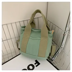 Dettaglio borsa tote in tela verde menta in cesto di metallo con tracolla oliva