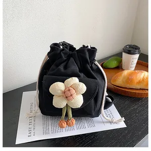 Close-up of black canvas bucket bag with a 3D fabric flower and drawstring closure