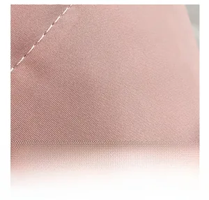 Macro view of pink polyester fabric with precise white stitching details on crossbody bag