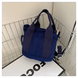 Dettaglio della borsa tote in tela blu scuro con manici robusti e tracolla nera regolabile