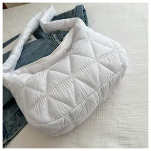 Detailed close-up of white quilted down-filled shoulder bag with triangle patterns