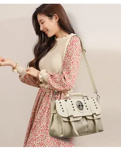 Detailed side view of beige retro crossbody bag with silver skull and metal studs