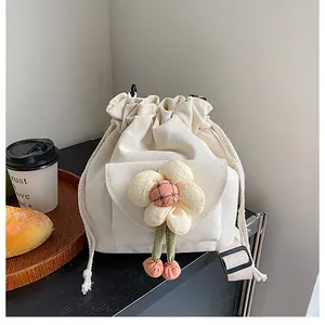 Detail of canvas bucket bag featuring plush flower decor and drawstring closure