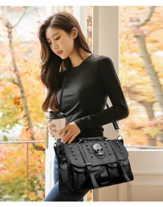 Close-up of black punk shoulder bag with silver skull ornament and metallic rivets detail