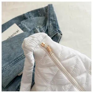 Close-up of golden metal zipper and diamond quilted stitching on white cloud bag
