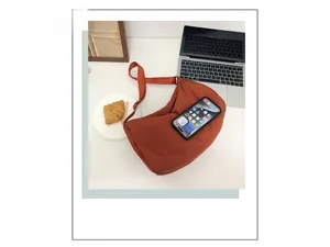 Top view of rust red nylon crescent bag next to a smartphone for size comparison