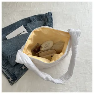 Spacious interior of white quilted shoulder bag with yellow lining and daily essentials