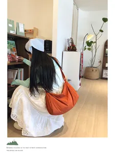 Burnt orange nylon crossbody bag shown worn by a model in a cozy, minimalist room setting
