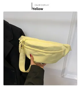 Detail of yellow canvas crossbody bag featuring woven rope zippers and adjustable strap