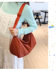 Detail view of the large crescent shoulder bag in burnt orange nylon on a model