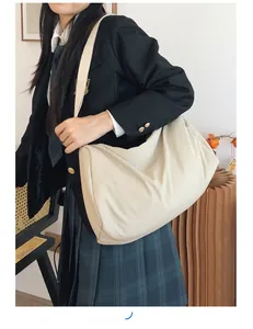Detailed view of beige oversized nylon cloud bag with wide shoulder strap on model