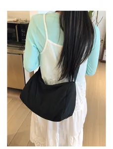 Black large capacity nylon crescent crossbody bag worn by a model in a casual setting