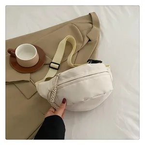 Detail of cream crossbody bag showing woven zipper pull and adjustable strap texture