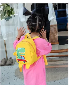Detail of yellow canvas dinosaur bag for kids shown on a young girl in a lifestyle setting