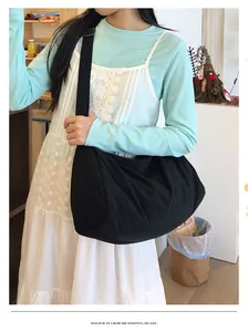 Detailed view of a large black nylon crossbody crescent bag worn by a female model