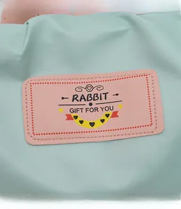 Détail du tissu en nylon imperméable vert menthe avec patch logo lapin rose et texte noir