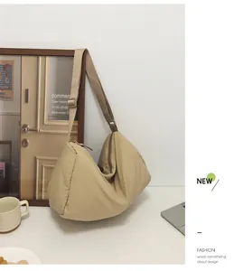 Detail view of beige quilted nylon dumpling bag with adjustable shoulder strap and zipper