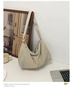 Detail of a large beige nylon crescent shoulder bag with adjustable strap in minimalist room