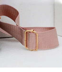 Détail de la bandoulière en nylon rose avec boucle réglable en métal doré sur le sac à dos