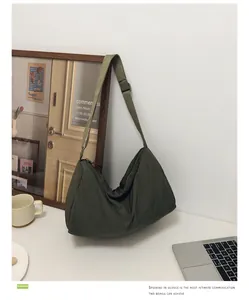Close-up of a dark green nylon crescent shoulder bag with a zipper on a minimalist desk