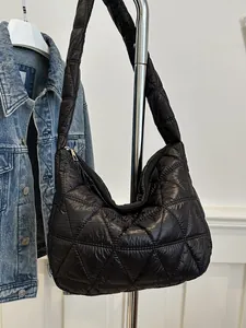 Black quilted puffer bag with triangle stitching and padded strap on metal display