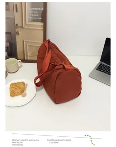 Detail view of a caramel nylon barrel travel bag with adjustable strap on a cafe table