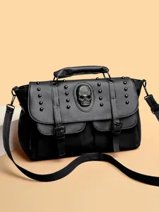 Retro black leather handbag with silver skull stud details and top handle on orange background