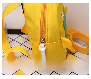 Detail view of the smooth silver zipper and green dinosaur pattern on a yellow toddler backpack