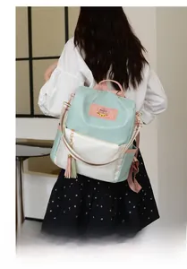 Vue détaillée du sac à dos Oxford menthe et crème avec pompons colorés et écusson