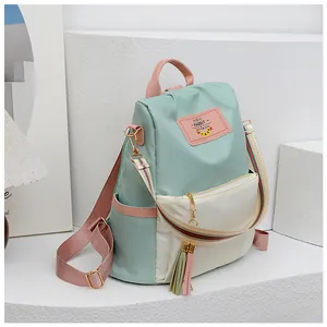 Détail du sac à dos en oxford avec bretelles rayées et pompon décoratif sur le zip