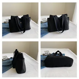 Detail of black canvas tote bag showing side pockets, magnetic snap button and wide straps